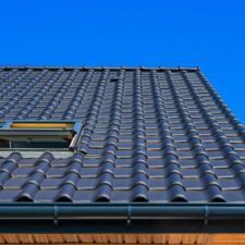 A vertical low angle closeup shot of the black roof of a building with a blue background