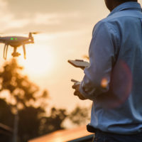 Man operating a drone with remote control, drone pilotage at sunset - Image